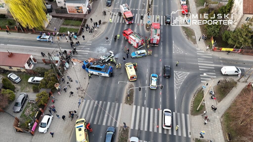Wielu ratowników medycznych i policjantów pracuje na miejscu wypadku drogowego, w którym przewrócił się autobus.