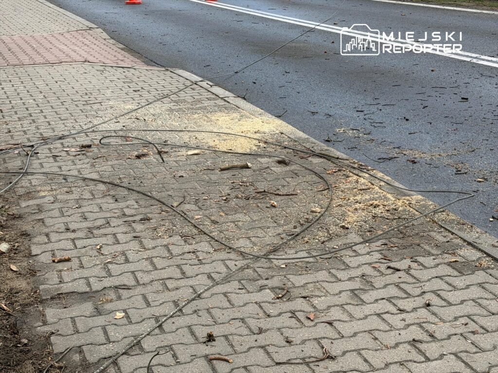 Na chodniku leżą porozrzucane kawałki drewna oraz splątane kable, obok widoczna droga.