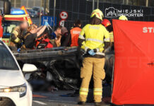 Grupa ratowników medycznych udziela pomocy poszkodowanym przy przewróconym pojeździe na drodze.