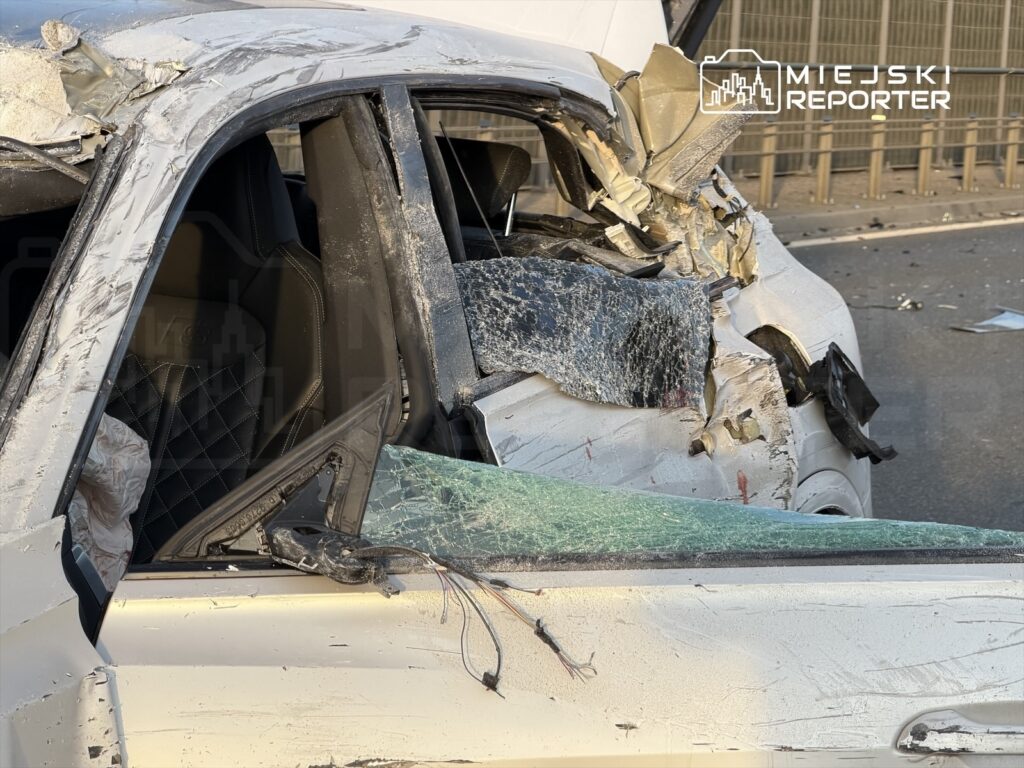 Zniszczony samochód z uszkodzoną karoserią i rozbitym oknem na drodze.