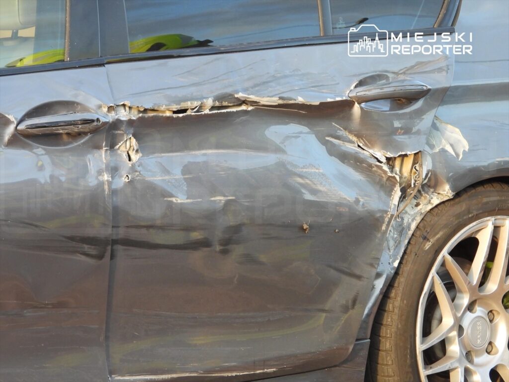 Uszkodzona karoseria samochodu osobowego z wgniecioną boczną częścią oraz zarysowaniami.