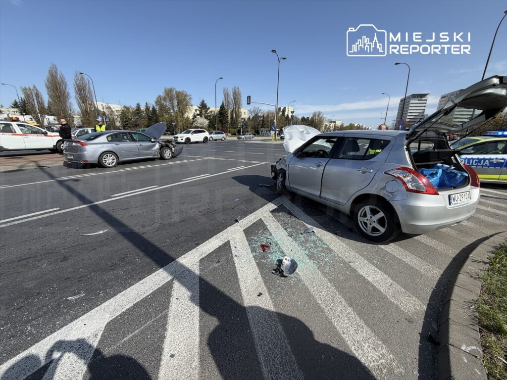 Zderzenie dwóch samochodów na skrzyżowaniu, z uszkodzonym pojazdem i rozbitym szkłem na jezdni.