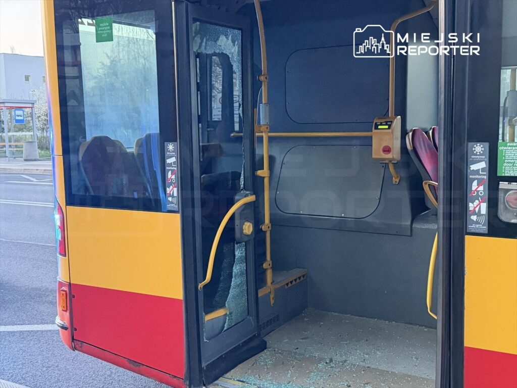 Szkło w drzwiach autobusu miejskiego jest rozbite, a wnętrze pojazdu jest puste.