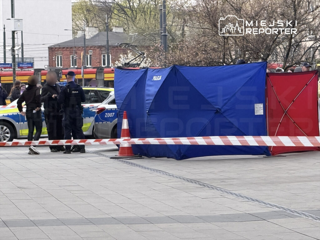 Policjanci rozmawiają z osobami na ulicy obok niebieskiego namiotu i radiowozu, otoczeni taśmą zabezpieczającą.