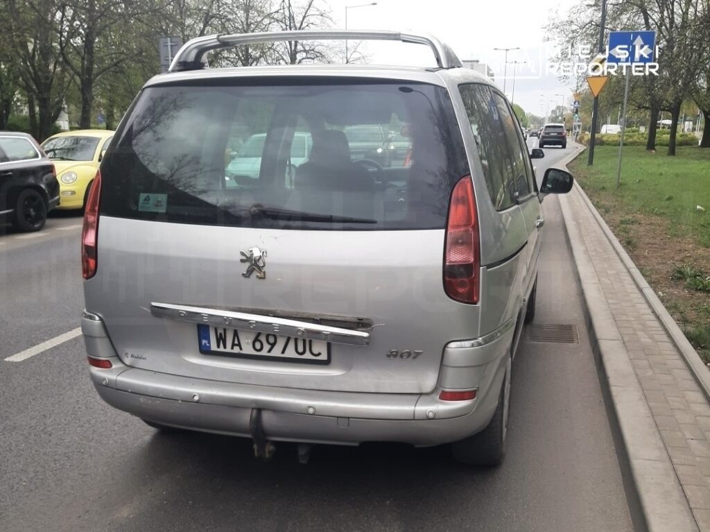 Srebrny samochód osobowy marki Peugeot 307 zaparkowany na ulicy, obok innych pojazdów.