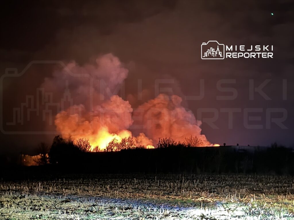 Wielka chmura dymu i ognia unosząca się nad horyzontem w ciemnej scenerii nocnej.