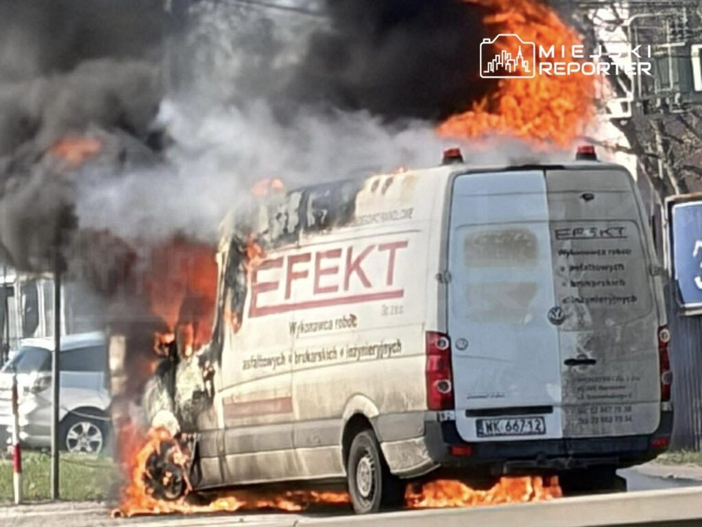 Wynajęty samochód dostawczy płonie na ulicy, wydobywając czarny dym i ogień z tyłu pojazdu.