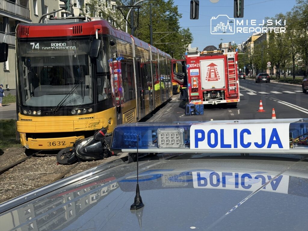 Tramwaj linii 74 zatrzymany na torowisku obok przewróconego motocykla, w tle woz strażacki i radiowóz policji.