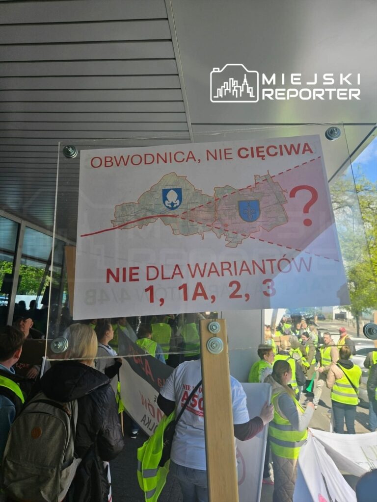 Transparent z napisem "OBWODNICA, NIE CIĘCIWA" oraz "NIE DLA WARIANTÓW 1, 1A, 2, 3" trzymany przez protestujących w kamizelkach odblaskowych.