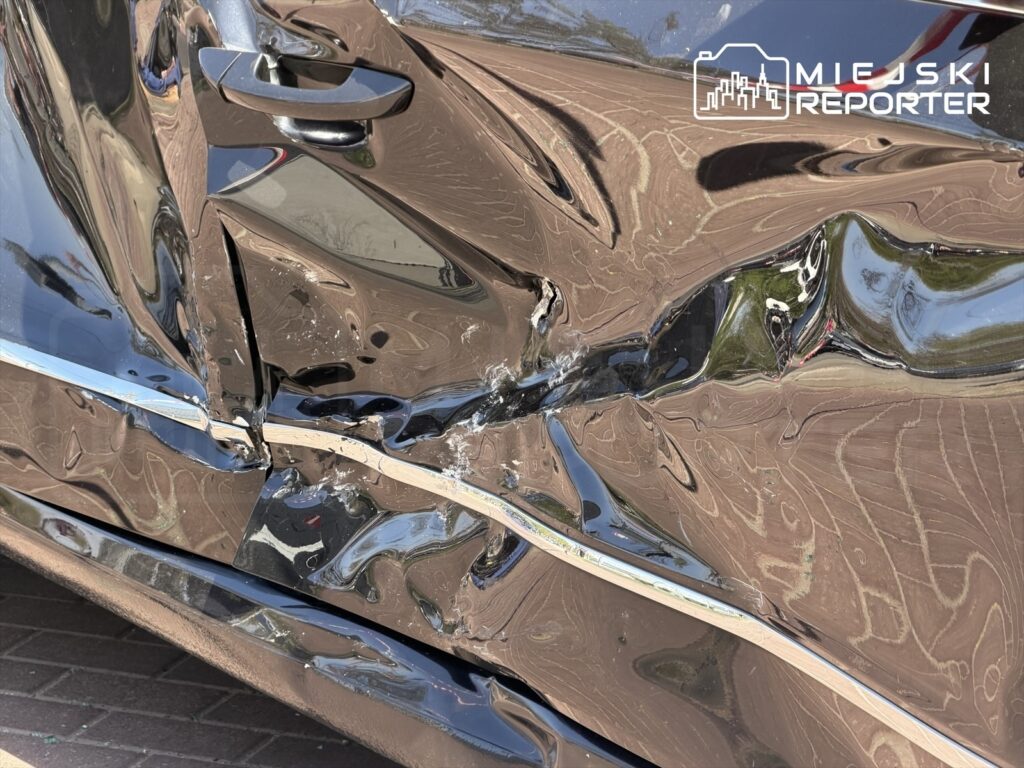 Uszkodzona karoseria czarnego samochodu osobowego z widocznymi wgnieceniami i zarysowaniami na drzwiach.