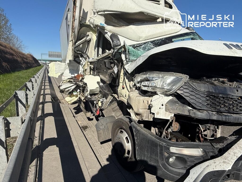 Uszkodzony samochód ciężarowy z wgniecioną kabiną stoi na poboczu drogi, obok barierki ochronnej.