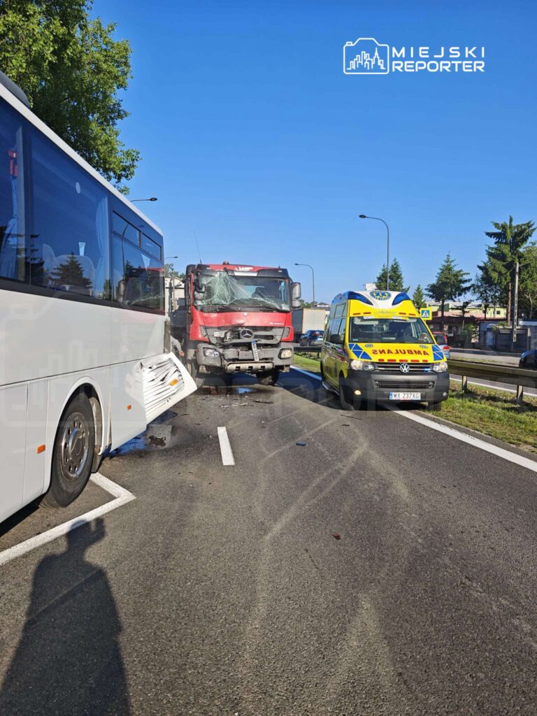 Wypadek drogowy z udziałem autobusu i uszkodzonej ciężarówki, obok stoi ambulans. Na drodze widoczne ślady po oponach.