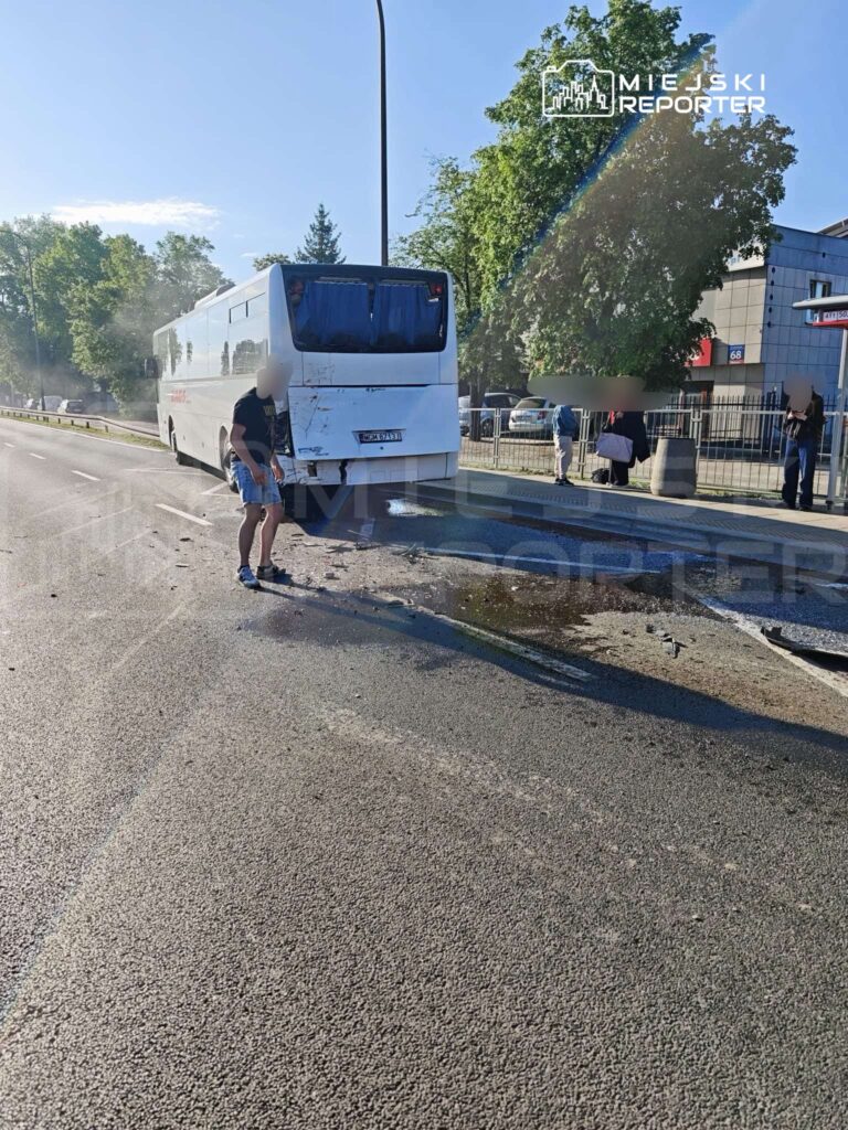 Mężczyzna w koszulce i szortach ocenia uszkodzenia autobusu, który zatrzymał się na jezdni po kolizji.