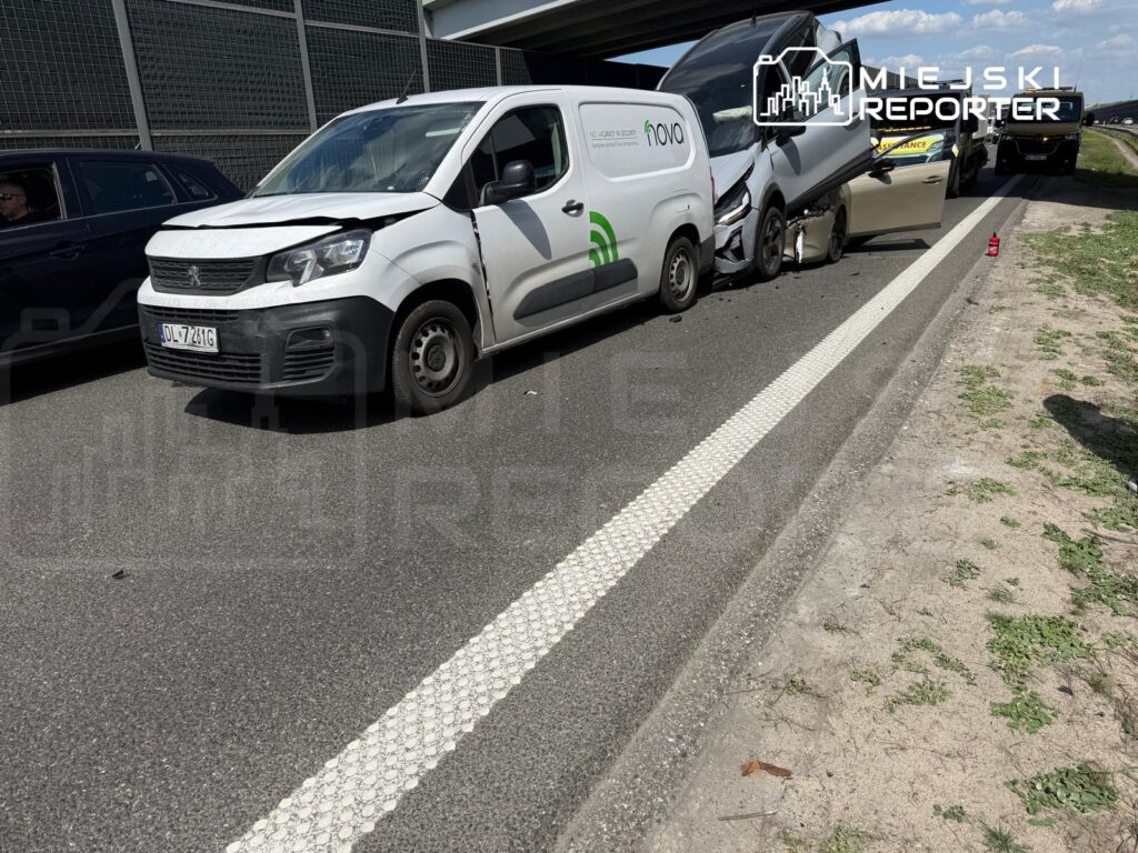Zderzenie dwóch samochodów dostawczych na drodze, z widocznymi uszkodzeniami przednich części pojazdów.