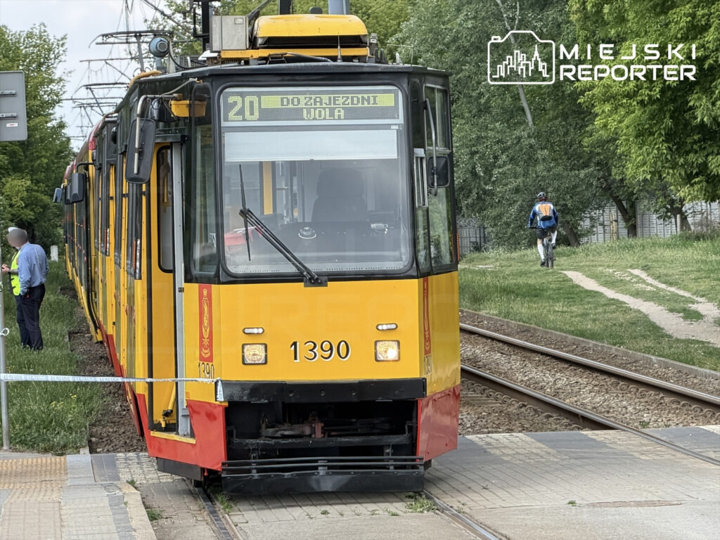 Tramwaj linii 20 zatrzymany na przystanku, obok stoi mężczyzna w niebieskiej koszuli rozmawiający z pracownikiem.