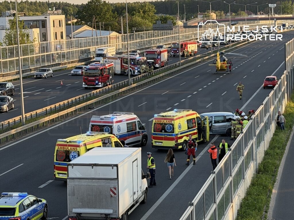 Na drodze autostrady ratownicy medyczni oraz strażacy udzielają pomocy poszkodowanym w wypadku samochodowym.