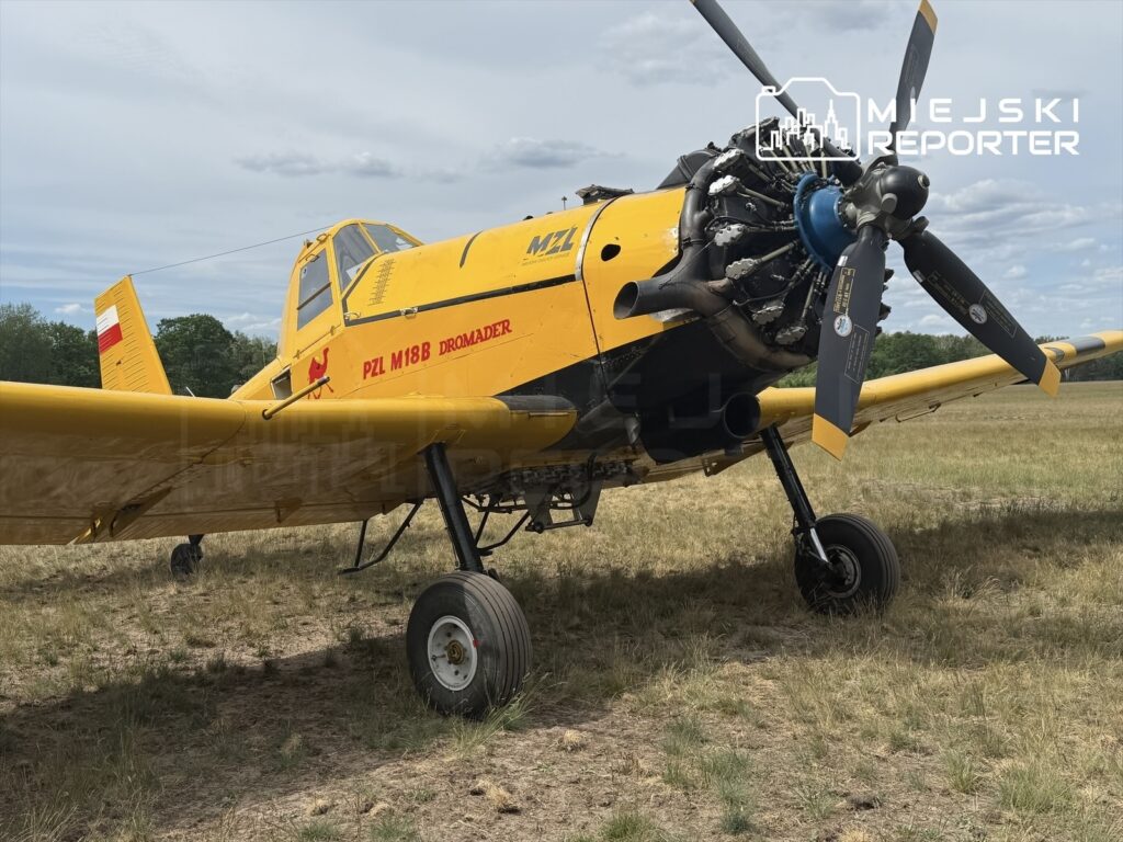 Żółty samolot PZL M18B Dromader stoi na trawiastym terenie, z widocznym silnikiem i wirnikiem.