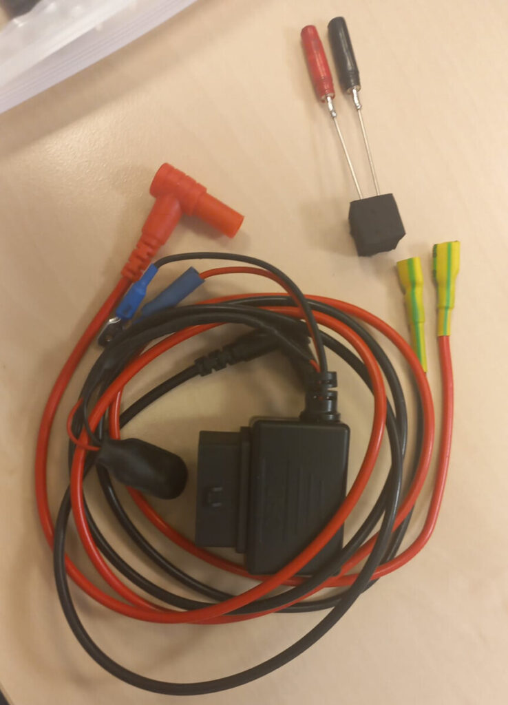 Kabelki elektroniczne w różnych kolorach oraz złączka, ułożone na jasnym stole.