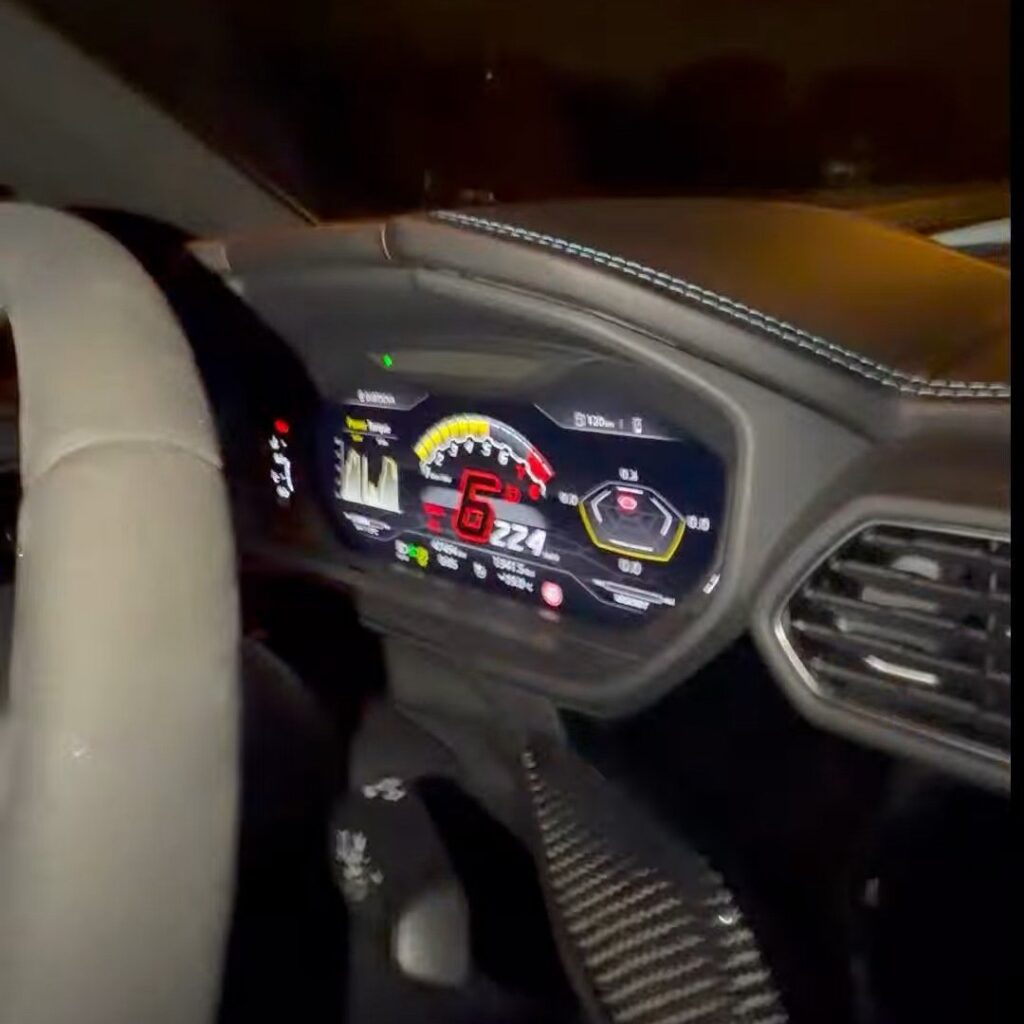 Wnętrze sportowego samochodu z widocznym cyfrowym wyświetlaczem prędkości, wskazującym 224 km/h.