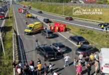 Na drodze ekspresowej zablokowane pojazdy, ratownicy medyczni i strażacy udzielają pomocy poszkodowanym, a tłum gapiów obserwuje sytuację.