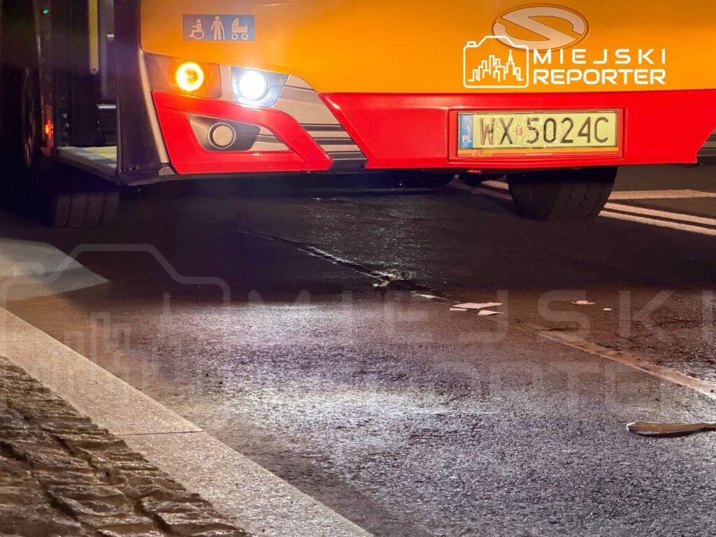 Autobus z widocznymi symbolami dostępu dla osób niepełnosprawnych i wózków dziecięcych stoi na oświetlonej ulicy.