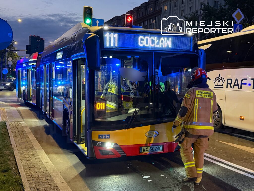 Autobus linii 111 zatrzymany na ulicy, obok strażaków w mundurach, z włączonymi sygnałami świetlnymi.