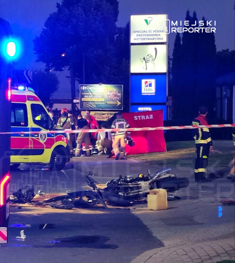 Ratownicy medyczni i strażacy udzielają pomocy poszkodowanym przy rozbitej motocyklu na ulicy, obok przychodni weterynaryjnej.