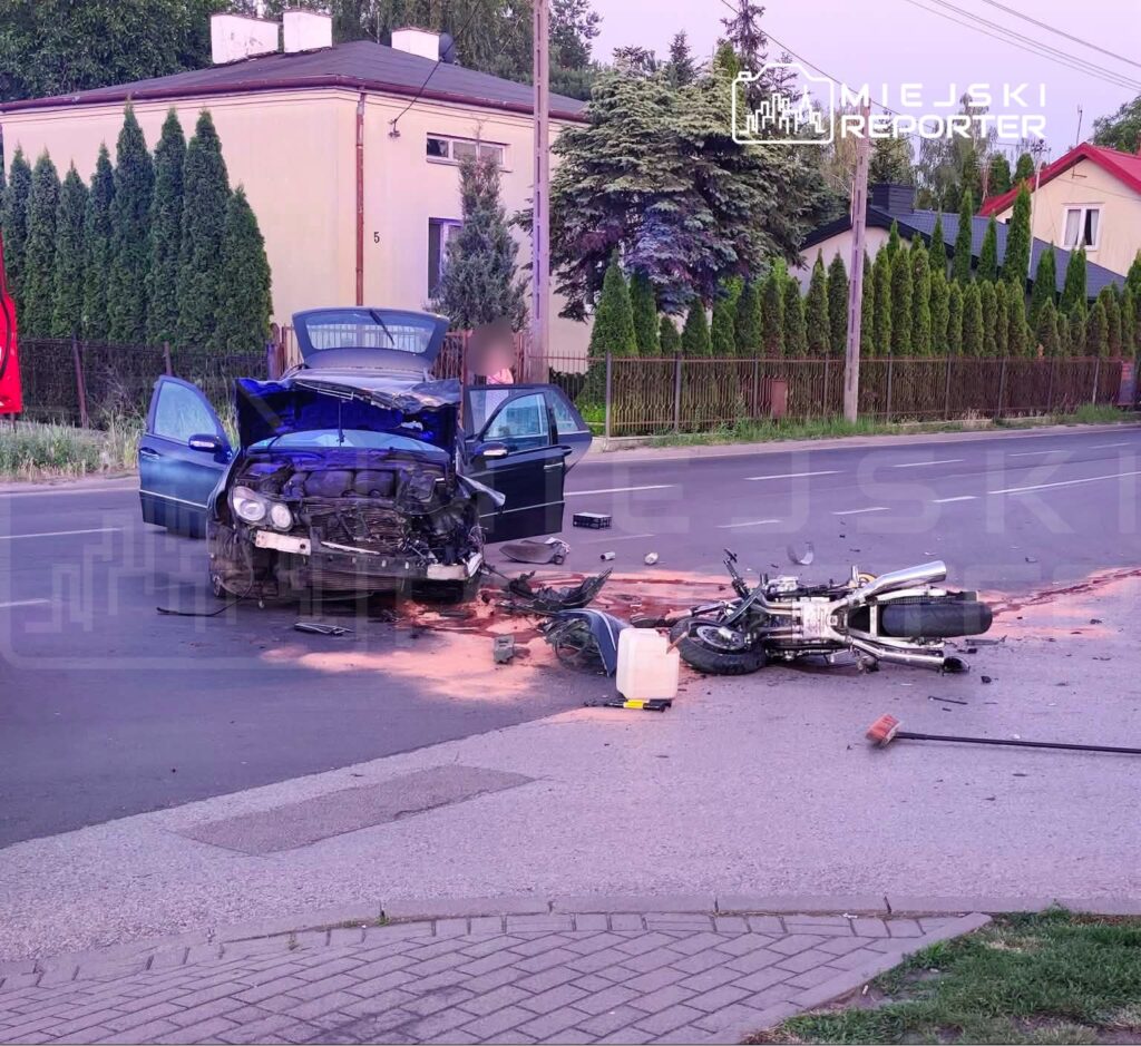 Zniszczony samochód osobowy stoi na drodze, obok leży przewrócony motocykl, a w tle widać zadrzewioną posesję.