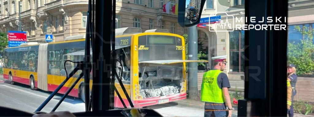 Kierowca autobusu przystankowego rozmawia z funkcjonariuszem w kamizelce odblaskowej na ruchliwej ulicy.