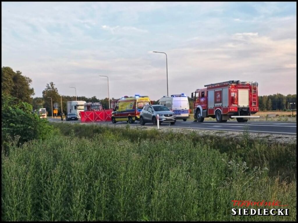 Na drodze widoczne pojazdy służb ratunkowych oraz samochody osobowe, z ustawioną barierą zabezpieczającą.