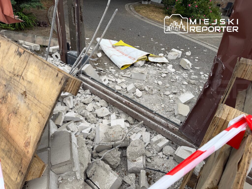 Rozbite betonowe elementy leżą na ziemi obok drewnianej deski i stalowych prętów w miejscu budowy.