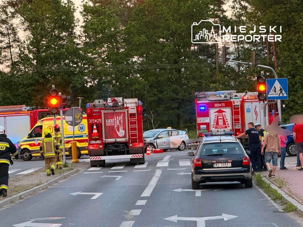 Na drodze zatrzymane pojazdy ratunkowe, w tym karetka i samochody straży pożarnej, podczas interwencji po wypadku.