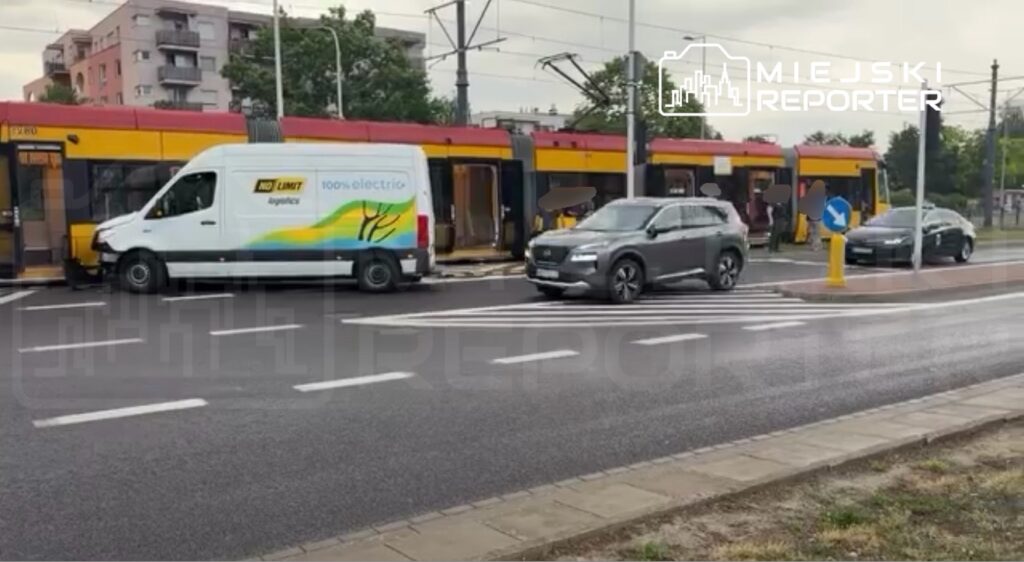 Biały samochód dostawczy z napisem "100% electric" zatrzymany obok tramwaju na przystanku w miejskim otoczeniu.