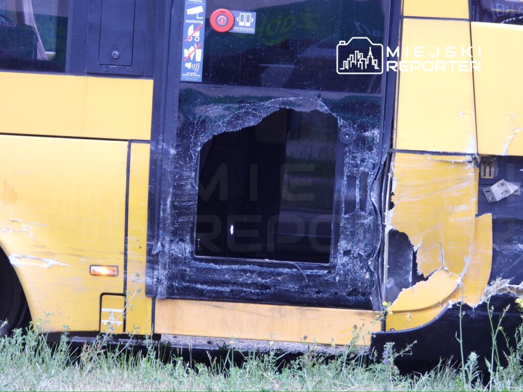Uszkodzony żółty autobus z otwartymi drzwiami, widoczne zniszczenia na karoserii i oknach.