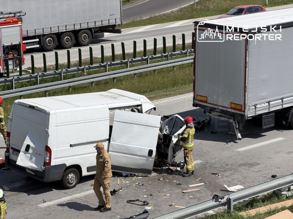 Na drodze doszło do wypadku, w którym zderzyły się dostawczy samochód i ciężarówka; strażacy udzielają pomocy poszkodowanym.