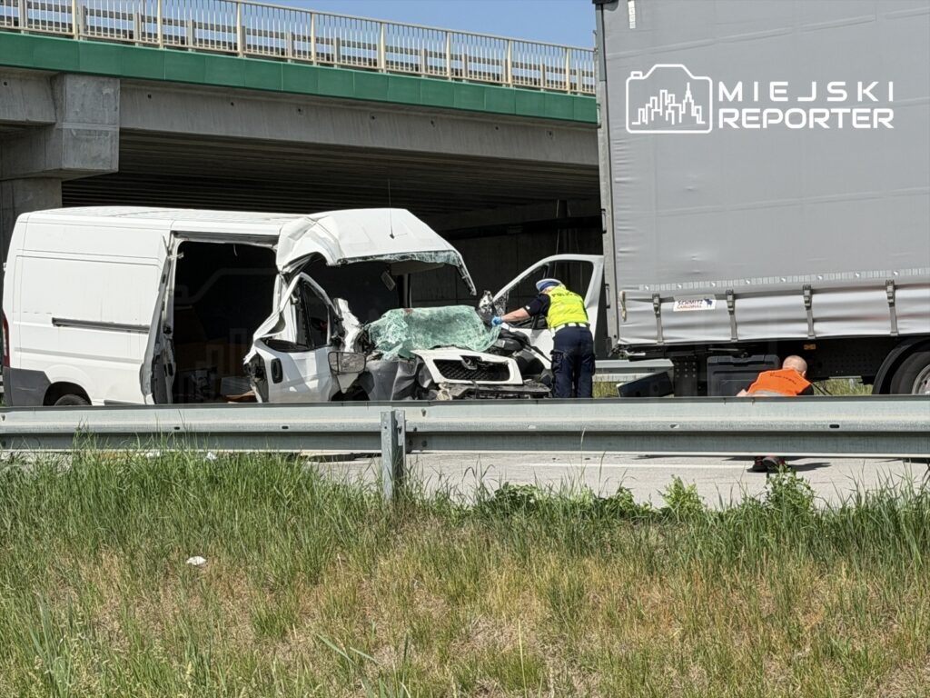 Wypadek drogowy z udziałem białego vana i ciężarówki, na którym pracują ratownicy medyczni.