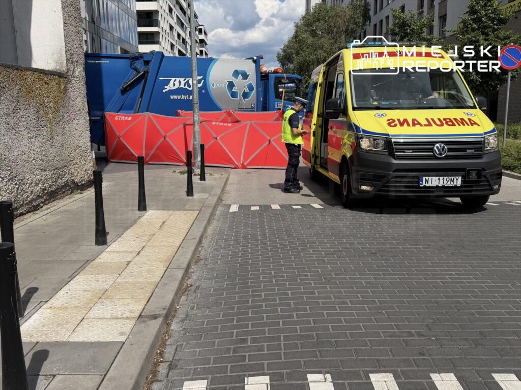 Karetka pogotowia oraz strażacy zabezpieczają teren w pobliżu budynku mieszkalnego, podczas akcji ratunkowej.