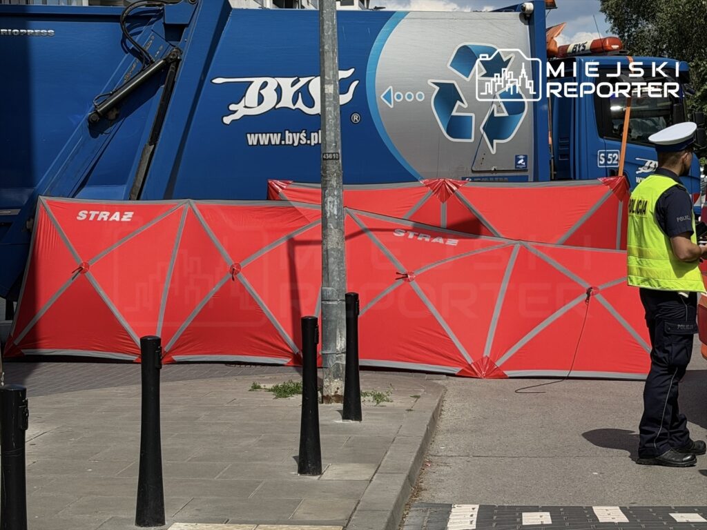Czerwony namiot strażacki ustawiony na chodniku obok niebieskiego pojazdu do recyklingu, policjant monitoruje sytuację.
