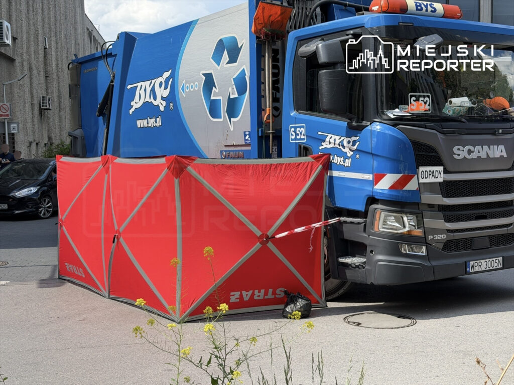 Czerwony namiot zabezpieczający ustawiony obok niebieskiego samochodu ciężarowego z logo firmy zajmującej się recyklingiem.