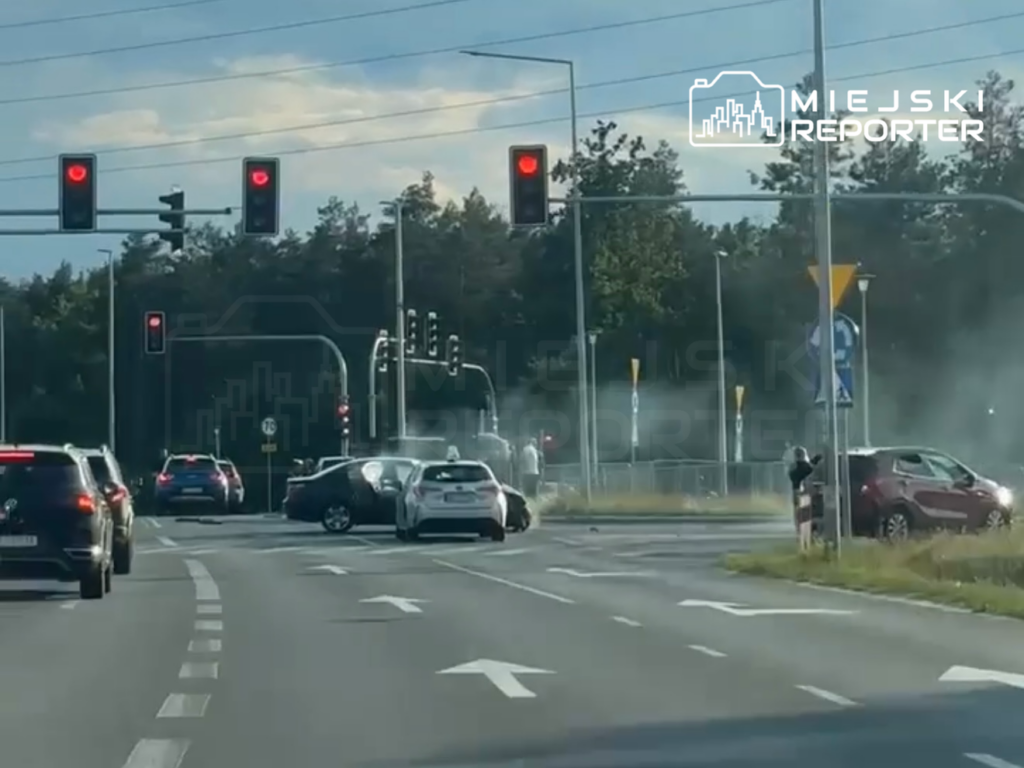 Wielu samochodów zatrzymanych na czerwonym świetle, jeden pojazd z uszkodzoną karoserią na skrzyżowaniu.