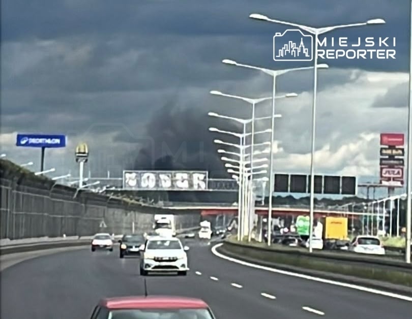 Na drodze ekspresowej widać samochody poruszające się w kierunku dymu wydobywającego się z oddali.