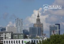Nowoczesne wieżowce i biurowce w Warszawie z charakterystyczną wieżą zegarową w tle, pod błękitnym niebem.