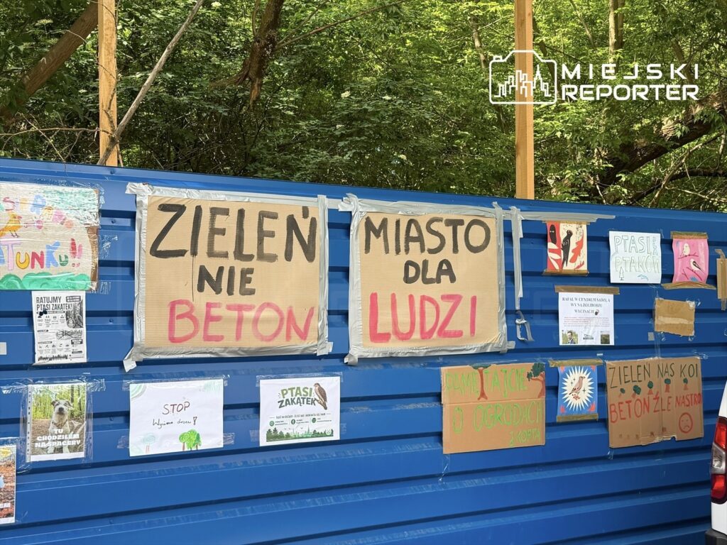 Na niebieskiej ścianie kontenera umieszczono transparenty z hasłami: "Zieleń nie beton", "Miasto dla ludzi" oraz inne rysunki i plakaty związane z ochroną przyrody.