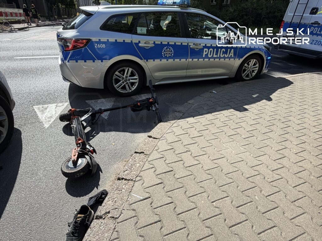 Policyjny radiowóz stoi na ulicy obok leżącej elektrycznej hulajnogi i porzuconego buta.