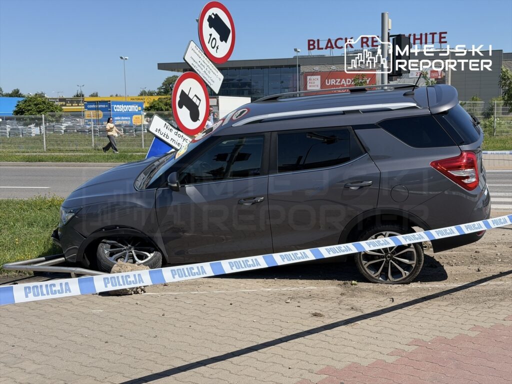 Samochód osobowy utknął na trawniku, otoczony taśmą policyjną, obok znaku drogowym z ograniczeniem prędkości.