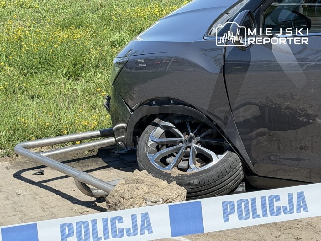 Samochód z unieruchomionym kołem na parkingu, obok widoczna taśma policyjna z napisem "POLICJA".