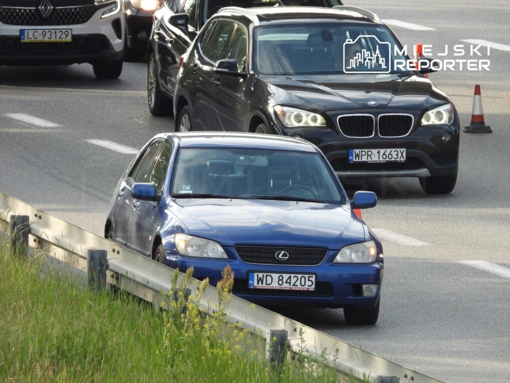 Niebieski samochód marki Lexus porusza się wśród innych pojazdów na ruchliwej drodze.