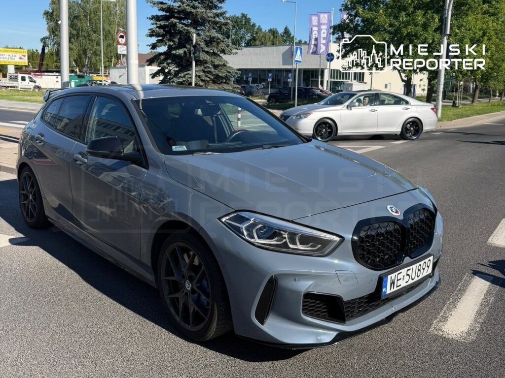 Nowoczesny samochód osobowy marki BMW w kolorze szarym stoi na drodze, obok przejścia dla pieszych.