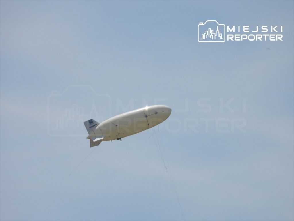 Biały balon sterowany unoszący się na niebie w słoneczny dzień.