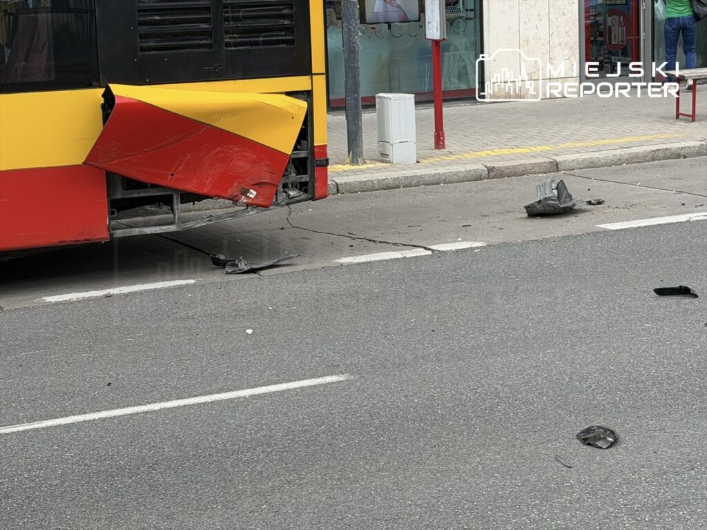 Uszkodzony autobus z otwartą częścią tylną stoi na ulicy, obok leżą fragmenty plastikowych elementów.